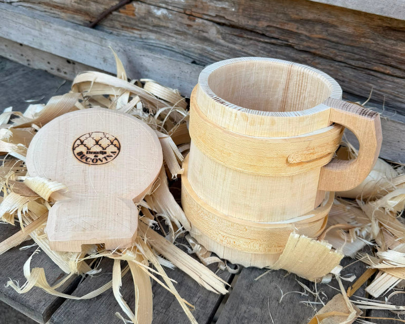 Cofă tradițională din lemn, cu capacul așezat lângă vas, pe un banc de lucru cu talaș